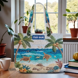 May include: A quilted tote bag featuring a beach scene with palm trees, sea turtles, and ocean waves. The bag has a blue label that says "YOUR NAME". The handles have a blue and white design.
