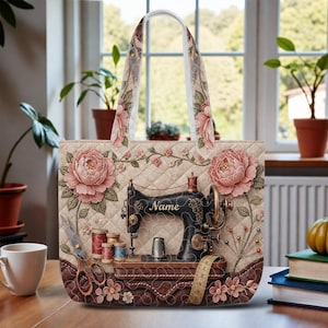May include: A beige quilted tote bag featuring a vintage sewing machine design with pink floral accents. The bag includes a handle with a floral pattern, a pair of scissors, spools of thread, and a measuring tape.
