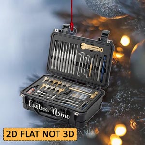 May include: A black, rectangular, hard-shell carrying case containing a variety of metal lock picking tools, tension wrenches, and practice keys. The exterior of the case features the white text Custom Name. The item hangs from a red string.