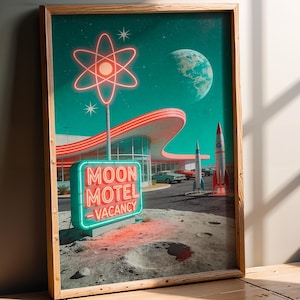May include: A framed art print featuring a retro-futuristic scene of a Moon Motel with a glowing neon sign, a mid-century modern building, two rockets, and vintage cars on a lunar surface under a teal sky with a large planet and an atom symbol.