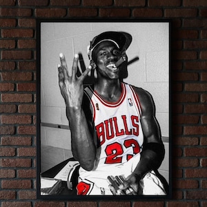 以下が含まれることがあります： シカゴ・ブルズのジャージを着たバスケットボール選手、背番号23の白黒フレームプリント。選手は3本の指を立て、口に葉巻をくわえています。