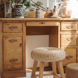 May include: A wooden vanity with drawers and a mirror, featuring a woven stool. The vanity has ornate drawer pulls and is adorned with decorative vases and plants. The stool has a round, woven seat and wooden legs.