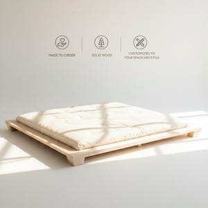 Peut inclure: Un lit plateforme bas de couleur claire avec un matelas crème. Le cadre de lit est en bois massif. L'image comprend le texte "MADE TO ORDER", "SOLID WOOD" et "CUSTOMIZED TO YOUR SPACE AND STYLE".