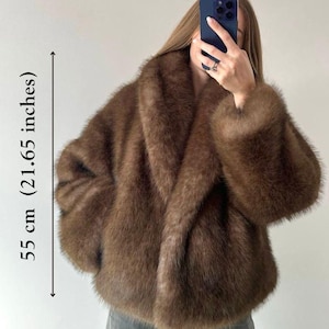 May include: Brown faux fur jacket, 21.65 inches in length, with a wide collar and long sleeves. The jacket has a soft, plush texture and a relaxed fit. A stylish outerwear piece for cooler weather.