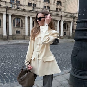 May include: A set of three ceramic mugs with a speckled, matte finish. The mugs are in shades of cream, light gray, and dark gray. Each mug has a simple, minimalist design, perfect for coffee or tea.