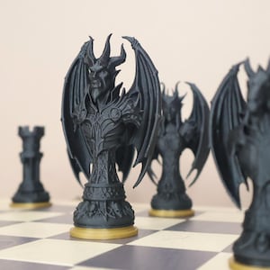 Puede incluir: Un juego de ajedrez negro con piezas de diseño intrincado, incluyendo figuras aladas y una torre. Las piezas de ajedrez están sobre un tablero a cuadros con una base dorada. Las piezas son de material oscuro.