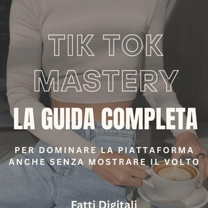 Può includere: Immagine con il testo bianco "TIK TOK MASTERY LA GUIDA COMPLETA". Una persona indossa una maglia a maniche lunghe grigio chiaro e jeans blu. Una tazza di caffè è su un tavolino.