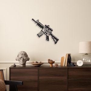 May include: Black metal rifle wall art with a scope, mounted on a cream wall. The rifle is angled, showing its detailed design. The image is of a decorative item, suitable for home decor.
