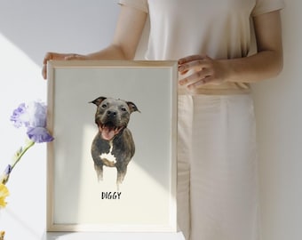 May include: A framed watercolor portrait of a smiling dog, predominantly gray and white, with the name "DIGGY" printed below. The artwork is in a light wooden frame, held against a neutral background. The dog's tongue is visible, and the overall style is artistic.