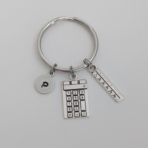 May include: Silver keyring with a calculator, ruler, and a charm with the letter "P" on it.