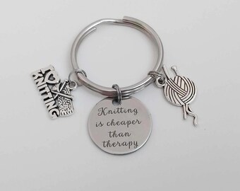 May include: Silver keychain with a charm that says "Knitting is cheaper than therapy" and other charms of yarn and knitting needles.