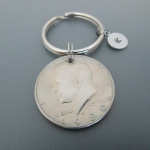 May include: Silver key chain with a 1980 US half dollar coin and a small silver charm with the letter K.