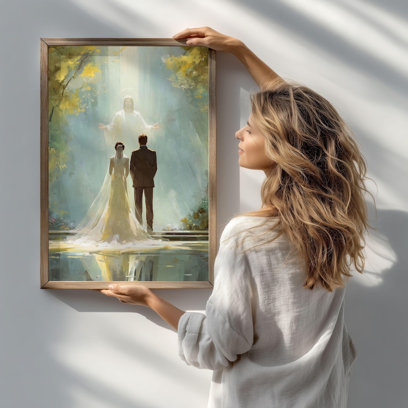 May include: A framed painting depicts a wedding scene with a bride in a white gown and a groom in a suit, standing before a figure in a bright light. The artwork has a soft, ethereal quality, with a wooden frame.