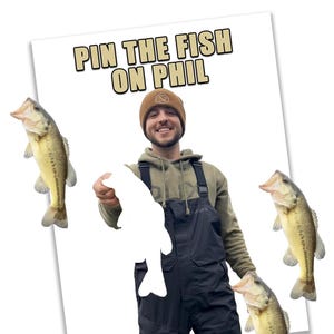 May include: A person holding a white fish cutout, with the text "PIN THE FISH ON PHIL" above them. Three fish are placed around the person. The person is wearing a brown beanie, green hoodie, and black overalls.