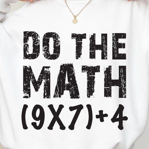 May include: White sweatshirt with the text "DO THE MATH" in a distressed black font. Below the text is the equation (9X7)+4. The sweatshirt is a casual style.