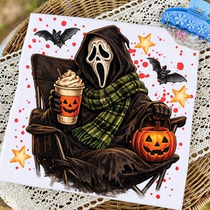 May include: A white square print featuring a cloaked figure with a white ghost mask, wearing a green plaid scarf, sitting in a chair. The figure holds a pumpkin-faced coffee cup and a jack-o'-lantern bucket, surrounded by bats, stars, and red dots.