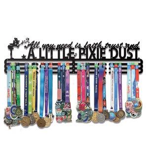 Puede incluir: Expositor de medallas de metal negro con el texto "All you need is faith, trust, and A LITTLE PIXIE DUST". Muestra numerosas medallas coloridas con cintas, mostrando logros de varios eventos.