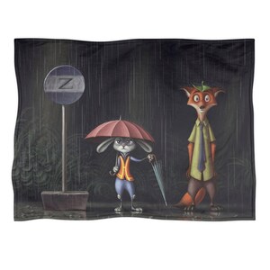 Może przedstawiać: Pluszowy koc z kresk&oacute;wkową ilustracją kr&oacute;lika i lisa stojących w deszczu pod parasolami. Kr&oacute;lik ma na sobie kamizelkę, a lis koszulę i krawat. Z tyłu znajduje się znak z literą "Z".