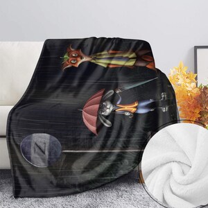 Może przedstawiać: Czarny koc z polaru z kresk&oacute;wkowym lisem i kr&oacute;likiem w deszczowej scenerii. Lis ma na sobie ż&oacute;łtą kamizelkę, a kr&oacute;lik trzyma czerwony parasol. Koc ma miękką, pluszową fakturę i jest narzucony na białą sofę.