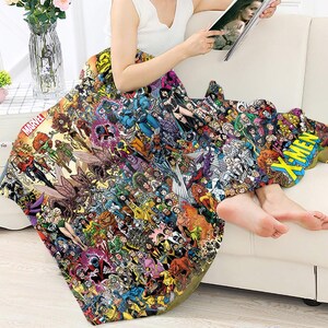 May include: A colorful blanket featuring a collage of Marvel comic book characters. The blanket has the Marvel logo and the word "X-MEN" in a yellow and blue design. The blanket is draped over a person.