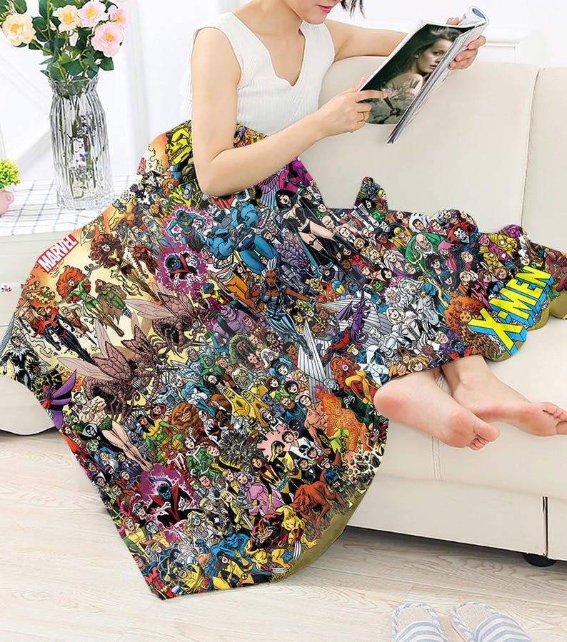 May include: A colorful blanket featuring a collage of Marvel comic book characters. The blanket has the Marvel logo and the word "X-MEN" in a yellow and blue design. The blanket is draped over a person.