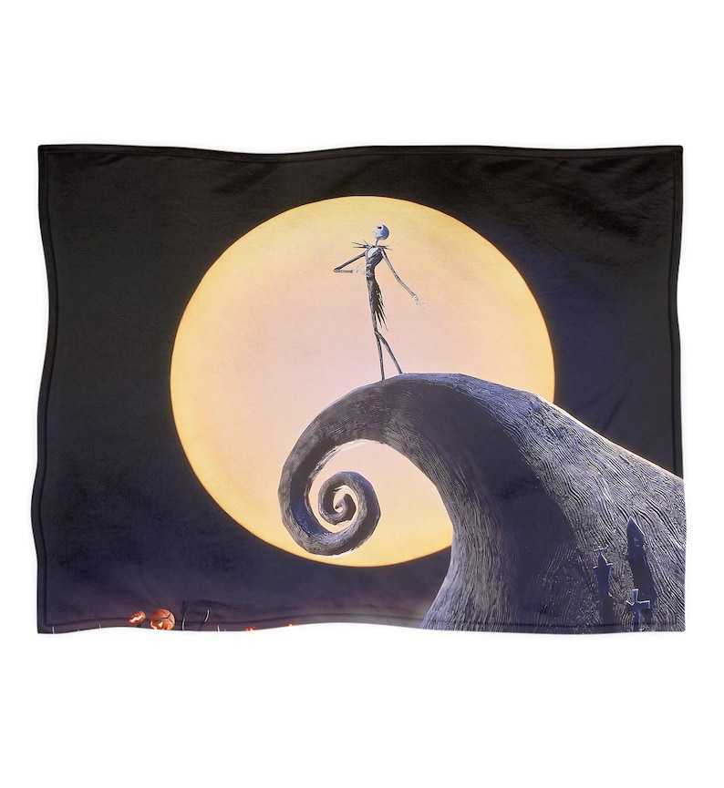May include: Black throw blanket featuring a scene from The Nightmare Before Christmas. Jack Skellington stands on a hill in front of a large, yellow moon. The blanket has a black border and a detailed, colorful image.