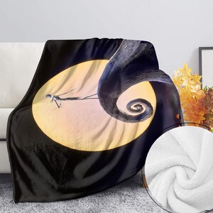 May include: A black and white throw blanket featuring a scene from The Nightmare Before Christmas. The design includes Jack Skellington in front of a full moon and a swirling, dark shape. The blanket has a soft, plush texture.