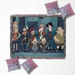 Könnte beinhalten: Eine gewebte Decke und drei Kissen mit Cartoon-Charakteren. Die Decke hat einen dunkelblauen Hintergrund mit einer Cartoon-Szene und Fransen. Die Kissen haben ein rosa-blaues Flamingomuster.