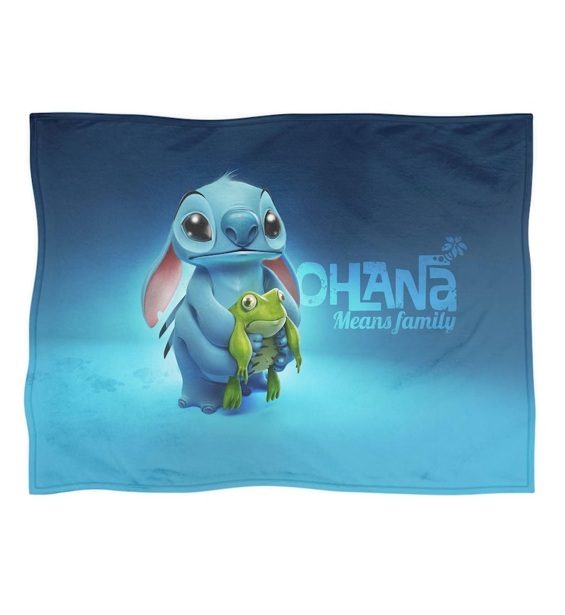 Pode incluir: Um cobertor azul com uma ilustra&ccedil;&atilde;o de desenho animado de Stitch de Lilo & Stitch segurando um sapo verde. O texto "OHANA Means family" est&aacute; em branco. O fundo &eacute; um gradiente azul.