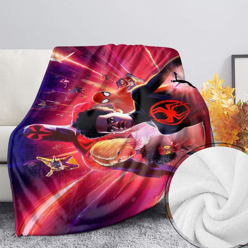 May include: A plush blanket featuring a vibrant illustration of a superhero in a dynamic pose, set against a backdrop of red and purple streaks. The design includes multiple characters and a spider emblem. The blanket is draped over a white couch.