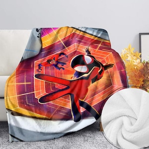 May include: A plush blanket featuring a vibrant graphic of Spider-Man in a dynamic pose, set against a geometric background with red, orange, and purple hues. The blanket has a white, soft underside.