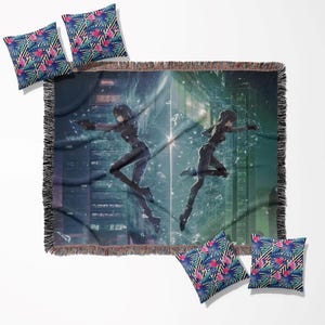 Op de afbeelding: Een geweven sprei en vier sierkussens. De sprei toont een futuristische anime-scène met twee figuren in zwarte pakken. De kussens hebben een blauw, roze en groen bloemenpatroon met zwart-witte strepen.