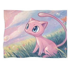 May include: A pink blanket featuring a cartoon illustration of a pink cat-like creature with large blue eyes. The background depicts a pastel landscape with grass, flowers, bubbles, and a cloudy sky. The blanket is rectangular.