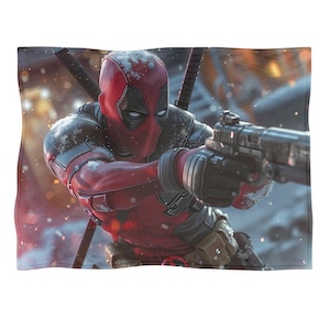 May include: A red and black Deadpool graphic blanket. The image shows Deadpool in his costume, holding a gun and looking to the right. The background is a snowy, action-packed scene.