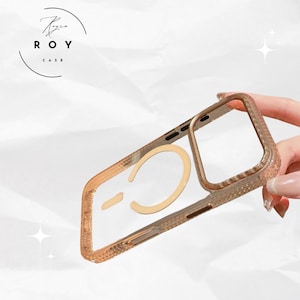 Puede incluir: Una funda de teléfono transparente y dorada con un diseño texturizado. La funda tiene un anillo dorado y el logotipo "ROY CASE". La funda está diseñada para proteger el teléfono.