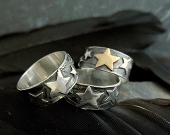 May include: Three silver rings with a star design. One ring has a gold star.
