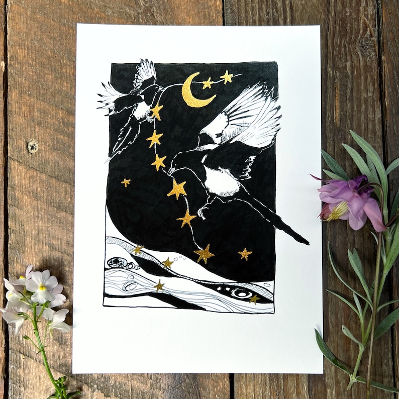 K&ouml;nnte beinhalten: Schwarz-Wei&szlig;-Illustration von zwei Elstern, die in einem Nachthimmel mit goldenen Sternen und einem Halbmond fliegen. Das Kunstwerk befindet sich auf wei&szlig;em Papier, mit dunklem Hintergrund, und wird von einer Holzoberfl&auml;che umrahmt.