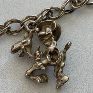 Puede incluir: Un eslab&oacute;n de pulsera con dije plateado que representa a un rat&oacute;n vaquero montando a caballo. El dije est&aacute; detallado con un sombrero de vaquero y una cuerda, sujeto a una cadena plateada. El dise&ntilde;o es de estilo vintage.