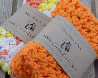 May include: Two orange, white, and yellow crocheted dishcloths with brown paper labels that read "Miss Jenny's Soap" and "100% Cotton Dish Cloth".