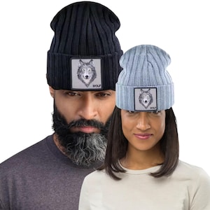 May include: Two ribbed knit beanies, one black and one light blue, each with a square patch featuring a wolf illustration and the word "WOLF". The beanies are worn by two people.