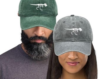 May include: Two baseball caps, one green and one gray, each embroidered with a white dinosaur skeleton. The caps have a classic, adjustable design. The green cap is worn by a person with a beard, and the gray cap is worn by a person.