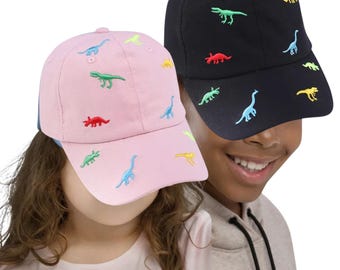 May include: Two baseball caps, one pink and one black, are displayed. Both caps feature embroidered dinosaur designs in various colors. The pink cap has a blue brim. The black cap has a curved brim and a matching black crown.