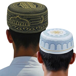 May include: Two embroidered skullcaps. One is black with gold embroidery, featuring an ornate design. The other is white with blue and gold detailing, showcasing an arched pattern. Both caps are round and appear to be worn.