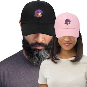 May include: Black and pink baseball caps with a cartoon character embroidered on the front. The black cap is worn by a person with a beard, and the pink cap is worn by a person with long hair.