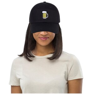 May include: Black baseball cap with a beer mug embroidered on the front. The beer mug is yellow with white foam and a black handle. The cap is made of a soft material and has a curved brim.