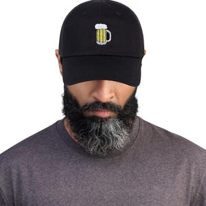 May include: Black baseball cap with a yellow and white embroidered beer mug design. The cap is made of a soft material and has a curved brim. A casual accessory for beer lovers.