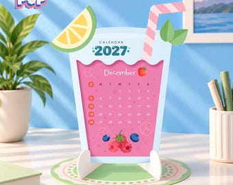 May include: A 2027 desk calendar shaped like a glass of pink fruit smoothie. The calendar features a lemon slice, a pink and white striped straw, and a December page with a strawberry, raspberries, and blueberries. It sits on a round coaster.
