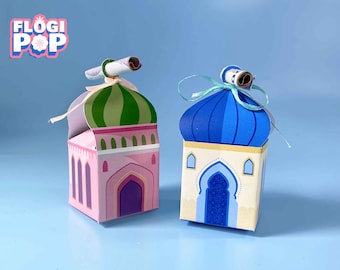 May include: Two decorative mosque-shaped boxes. One is pink with a green and white striped dome, the other is cream with a blue dome. Both have a scroll on top and are tied with ribbon. The boxes are labeled "FLOGI POP".
