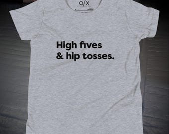 Puede incluir: Camiseta gris jaspeado con el texto negro "High fives & hip tosses". La camiseta tiene cuello redondo y mangas cortas. El logotipo de la marca es visible en la parte superior.