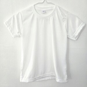 Könnte beinhalten: Ein schlichtes, weißes T-Shirt mit kurzen Ärmeln, das an einem Metallbügel hängt. Das Shirt hat einen Rundhalsausschnitt und ein Etikett im Nacken. Die Ärmel sind umgeschlagen. Der Stoff ist glatt und blickdicht.